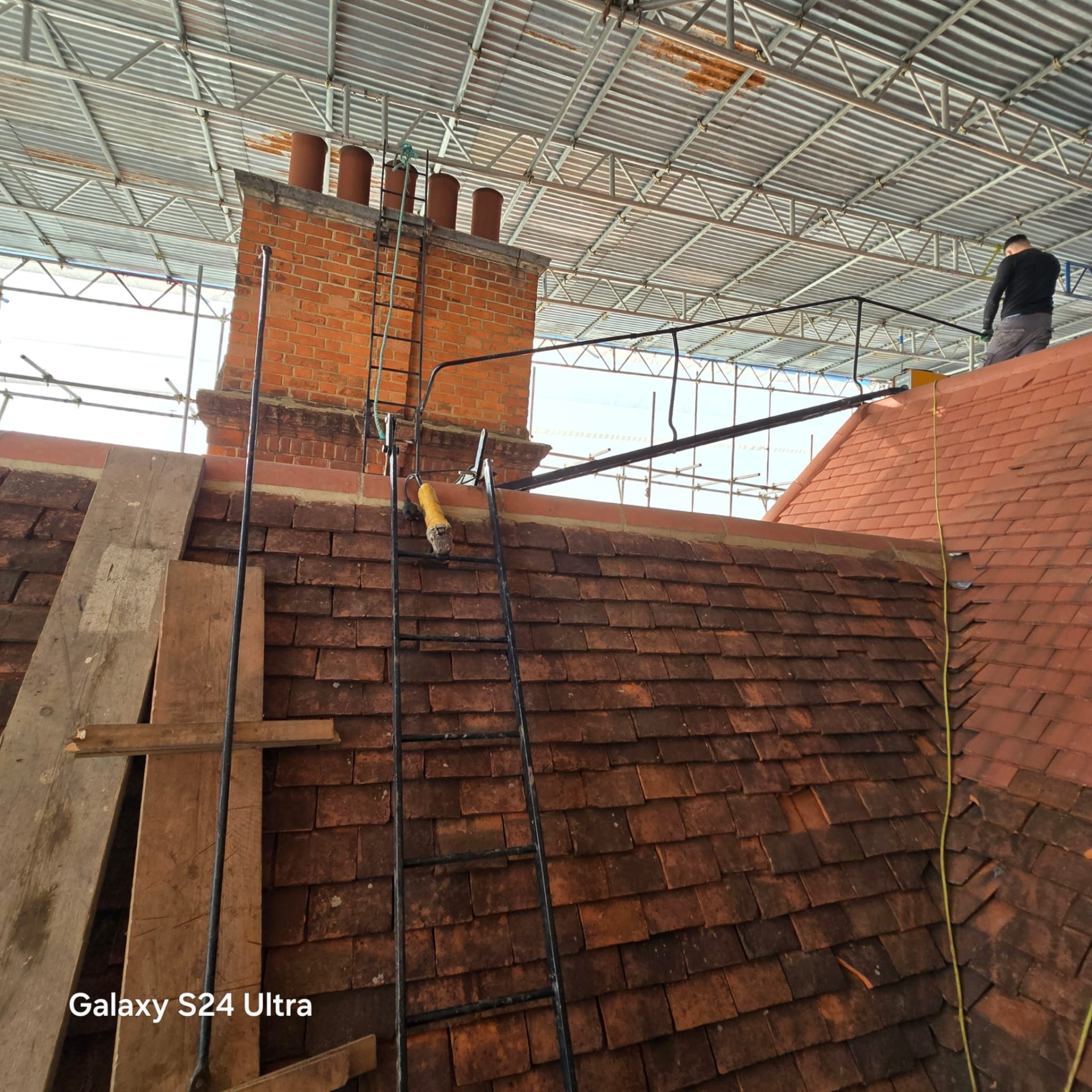 Weathered original clay plain tiles and a brick chimney stack awaiting stripping and renewal