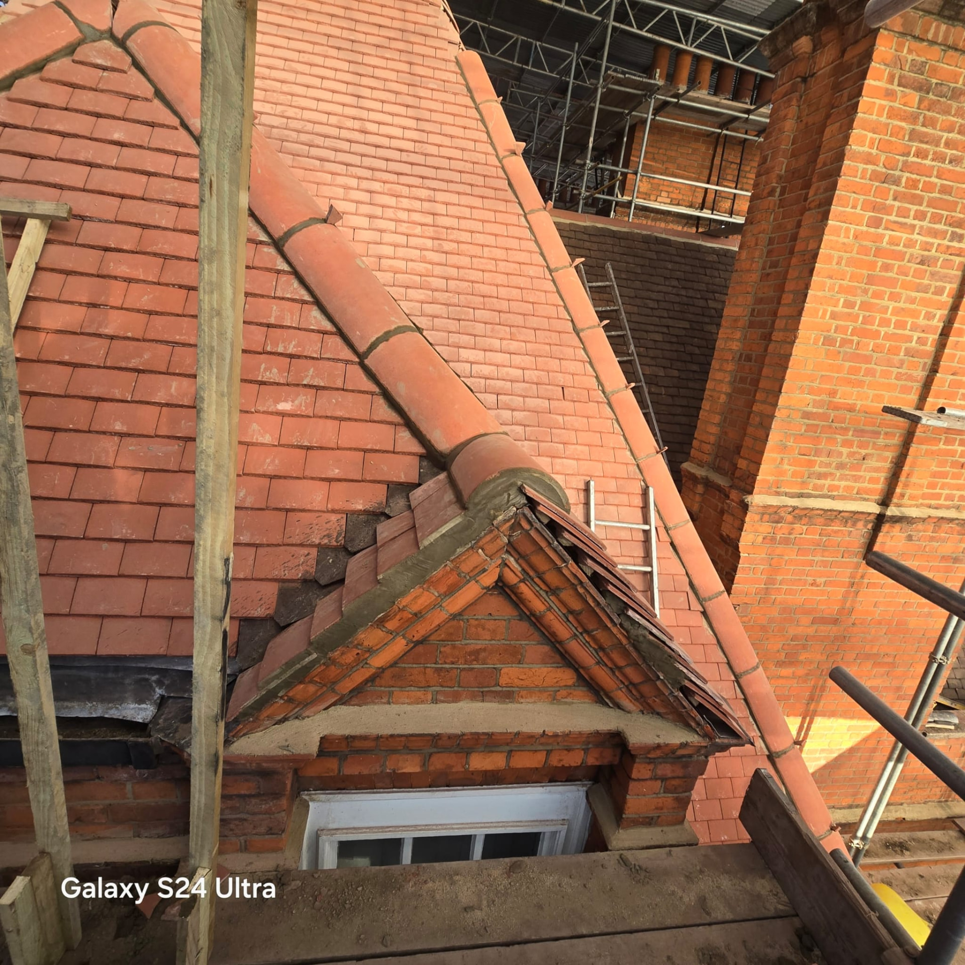 New clay plain tiling with bonnet hip tiles around a restored brick dormer