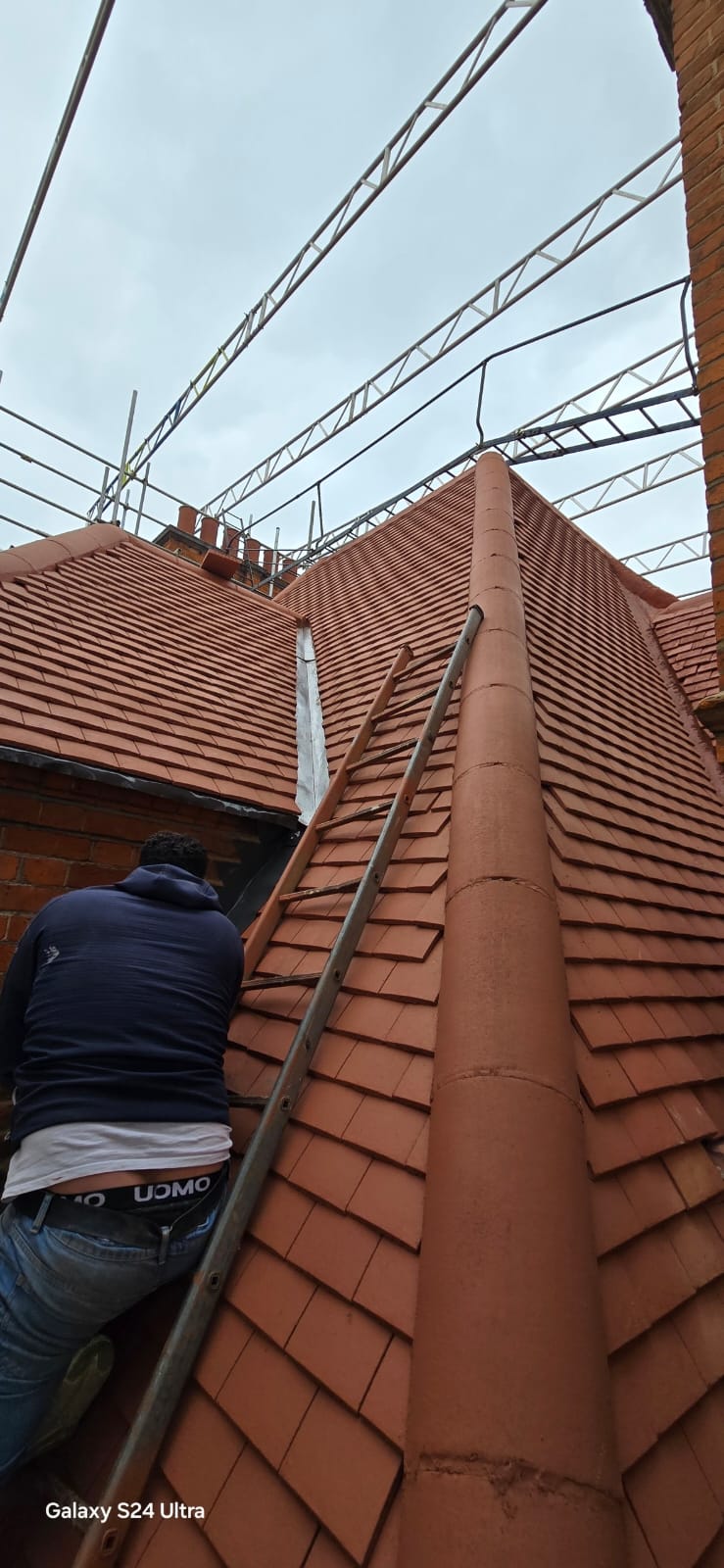 Roofer setting out clay plain tiles up the main slope of the listed building