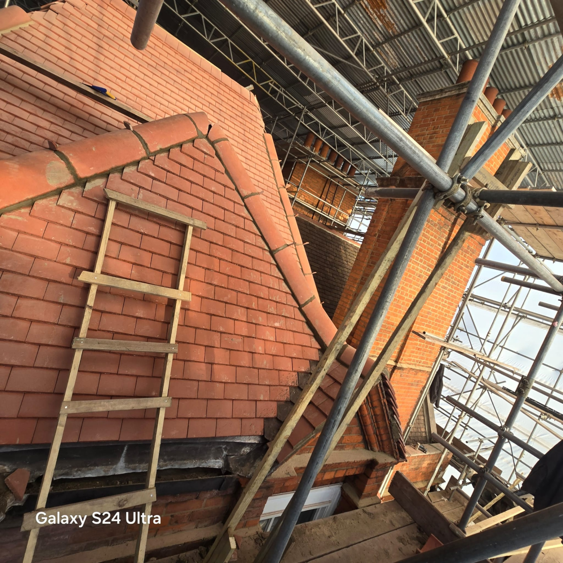 Hand cut valley and hip detail in new clay plain tiles above rebuilt brickwork