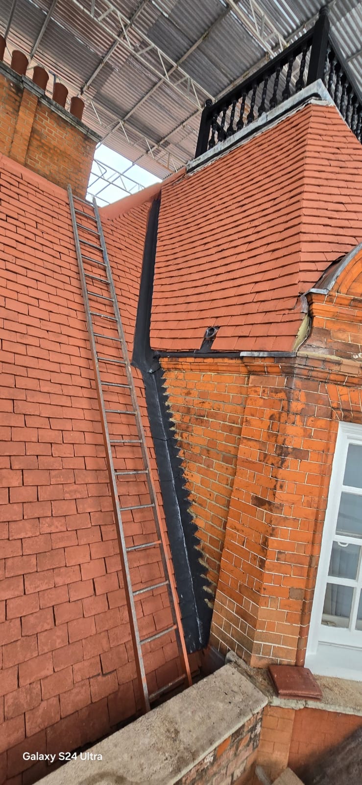 Lead soakers and stepped flashing dressed into the brick abutment beside a tiled slope