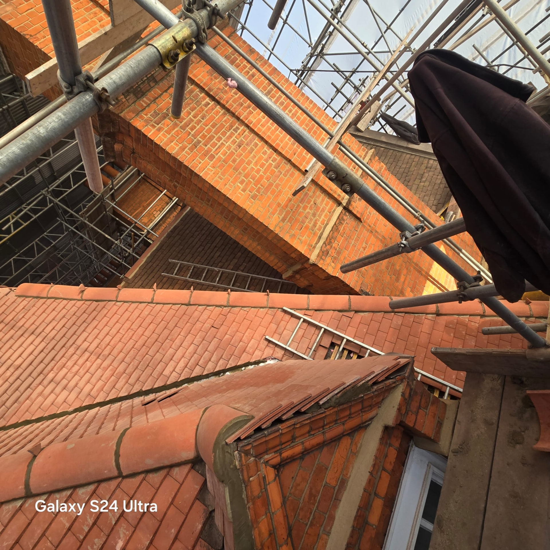 Newly tiled slopes, half round ridge and brick gables of the listed roof seen from below